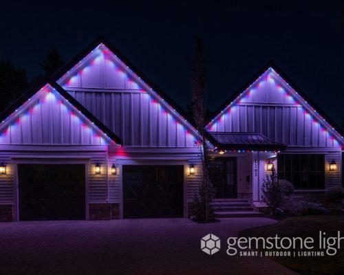 A modern farmhouse-style home adorned with vibrant, multicolored LED lighting along its gable roofs and eaves, creating a festive ambiance at night.