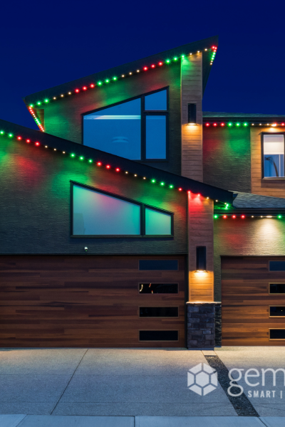 Modern house decorated with colorful Christmas lights on its roof and garage at night, showcasing innovative outdoor lighting solutions by Halo Lighting.